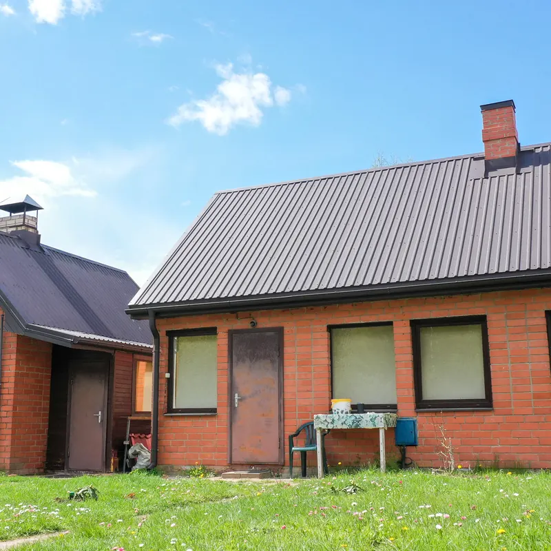 Tumši pelēks metāla jumts ķieģeļu privātmājai