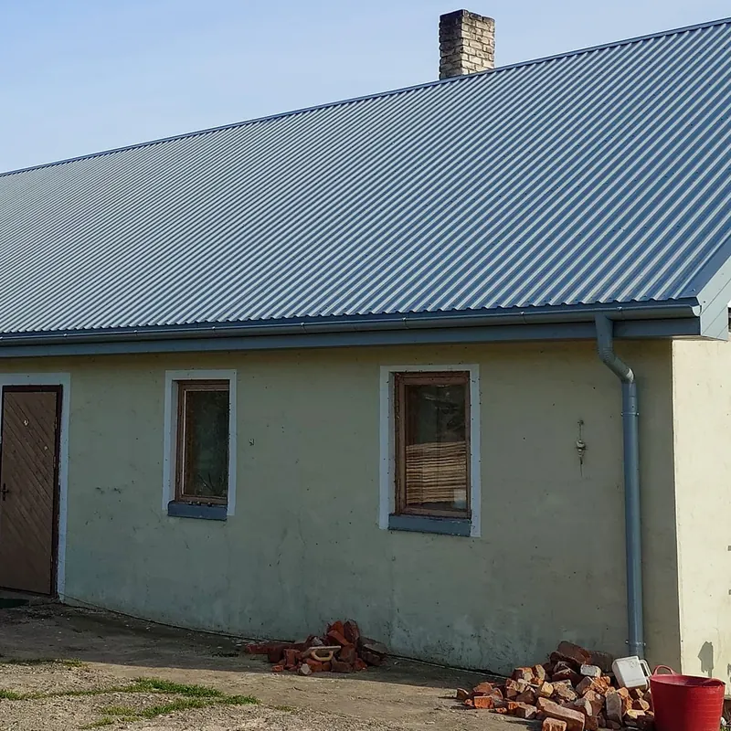 Pelēks profilēta metāla jumts vienstāva mājai