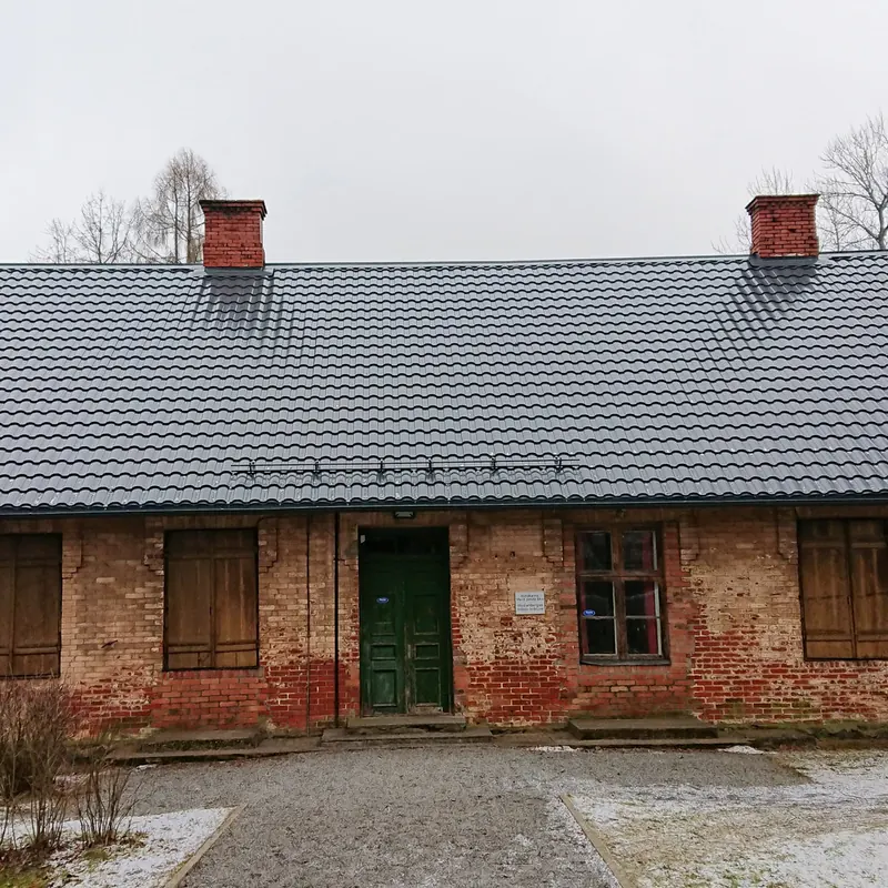 Pelēks metāla jumts vecai ķieģeļu ēkai