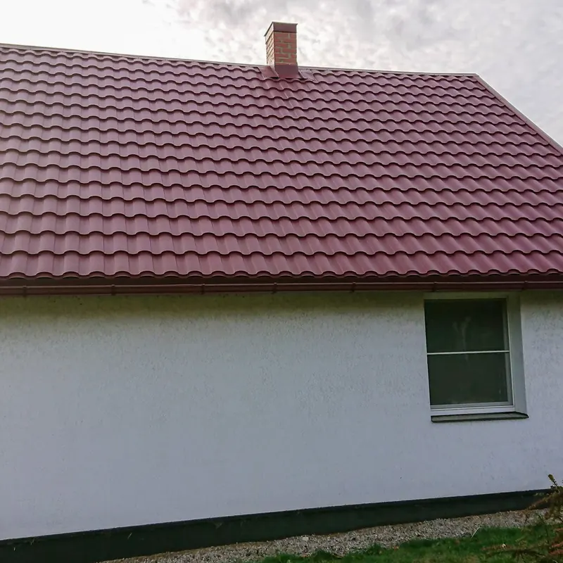 Tumši sarkans dakstiņu jumts baltai privātmājai